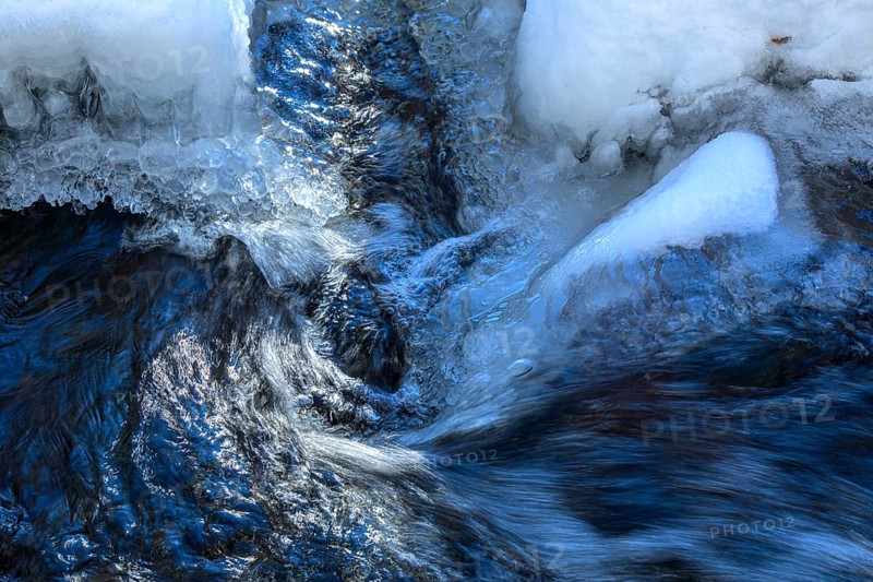 Ilsenburg, Saxony-Anhalt, Germany, Flowing water breaks through thick layers of ice in winter on the Ilse river in the Harz National Park on the Heinrich-Heine trail Ilsetal hiking trail