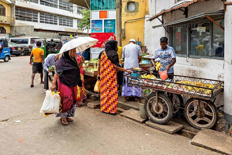People shop at market stalls in a lively street scene, people on the streets of Slave Island in Colombo Sri Lanka