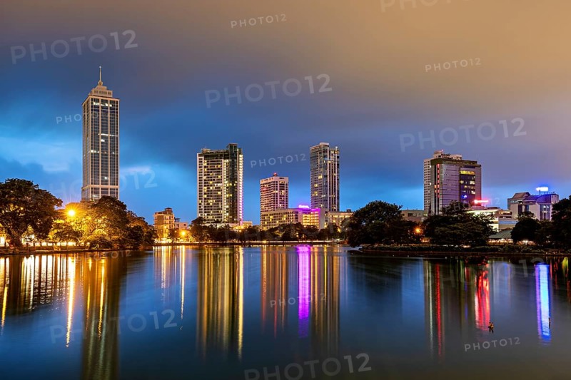 Nighttime cityscape with illuminated skyscrapers and reflections in the lake, the skyline of Colombo Sri Lanka at night