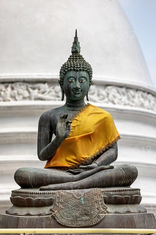 Bronze Buddha statue with yellow cloth in front of a white temple, The Seema Malaka Temple with the Buddha statues in Colombo Sri Lanka