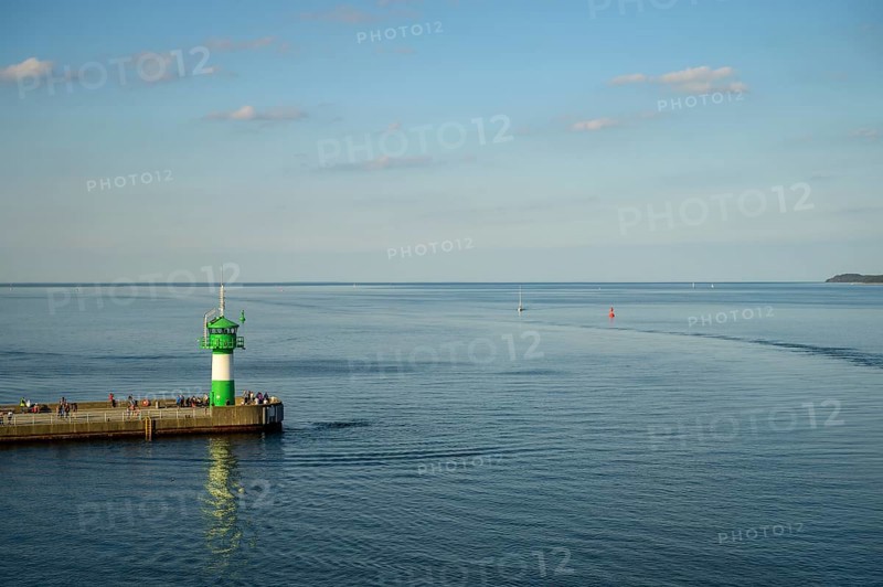 A green lighthouse harbour fire stands on a pier at the port exit of Travemünde in front of a calm, blue sea and a clear sky, Lübeck-Travemünde, Schleswig-Holstein, Germany