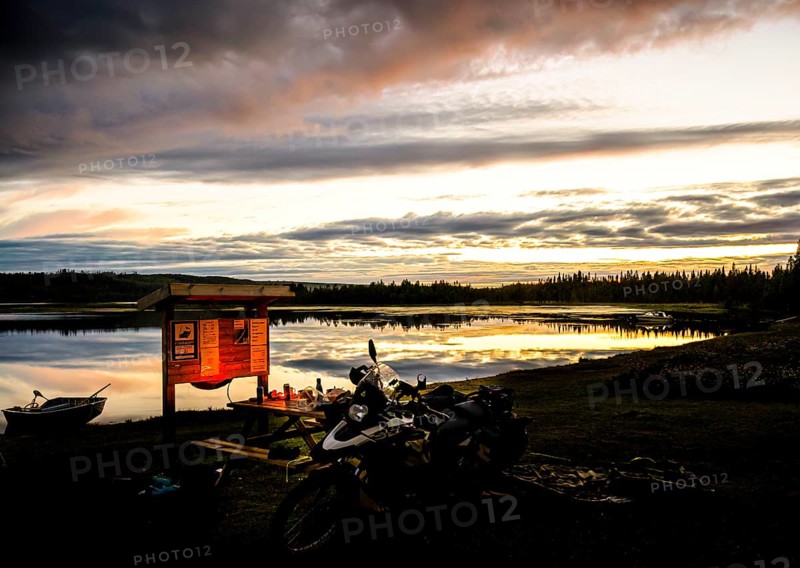 A BMW model G 650 GS Sertao motorcycle stands in front of a lake at sunset with dramatic clouds in the sky and reflecting water surfaces Dorotea, Västerbottens län, Sweden