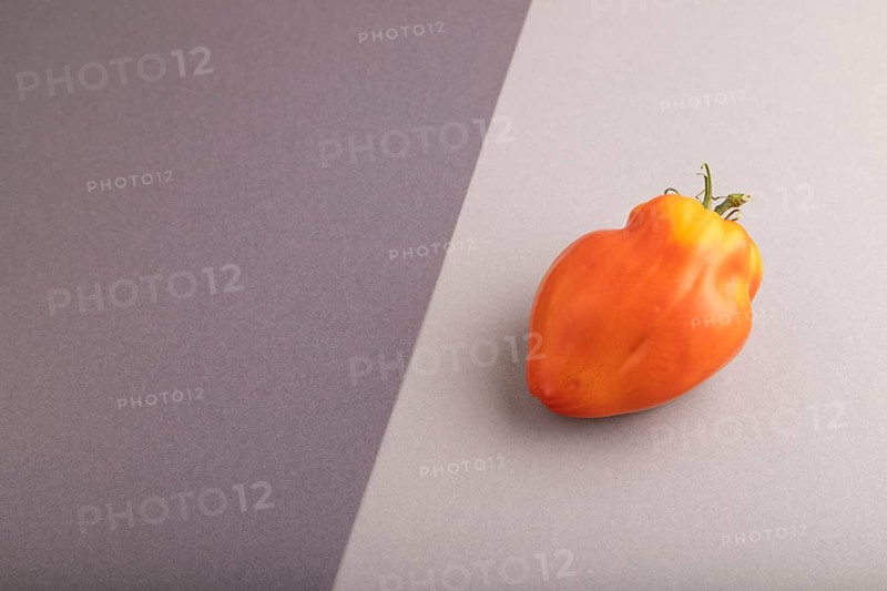 Red Heart Shape tomato on black and gray pastel paper background. Side view, copy space. healthy food, vegetable, minimalism