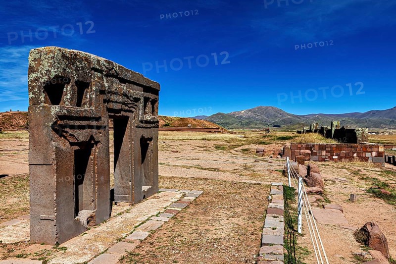Ancient stone structures in a vast, mountainous landscape under clear blue skies, the archaeological site with the ruins of Tiwanaku in Bolivia