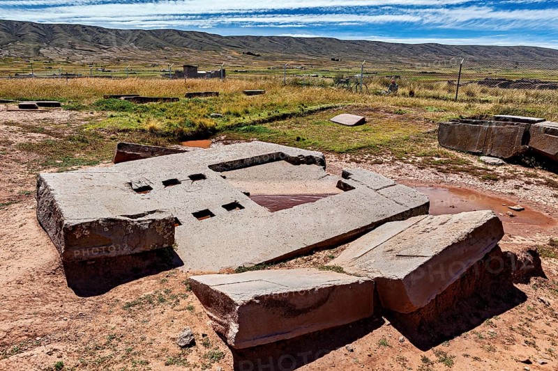 Large stone blocks and ruin structures on dry soil under a far-reaching sky, the archaeological site with the ruins of Tiwanaku in Bolivia