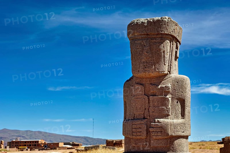 Large ancient stone statue under clear sky, showing detailed engravings, the archaeological site with the ruins of Tiwanaku in Bolivia
