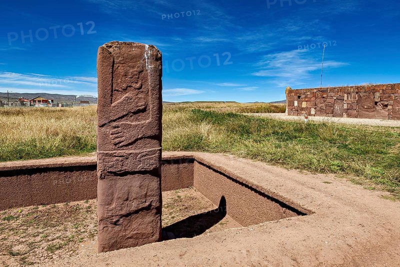 Upright ancient stone column in scenic surroundings under blue sky, The archaeological site with the ruins of Tiwanaku in Bolivia
