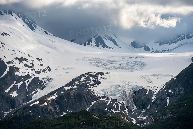 Mountain peak with Worthington Glacier glacier, dramatic cloudy sky, picturesque landscape on Richardson Highway, Chugach Mountains, Alaska, USA