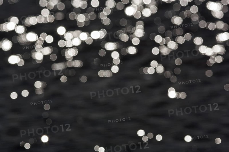 Abstract black background, sparkling white lights, bokeh balls, light reflections on water surface, octagonal light spots, copy space, background image, Sicily, southern Italy, Italy