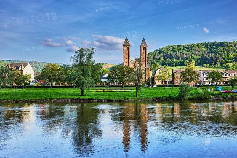 Moselle river, St. Salvator church, double tower, general architecture, houses, riverbank, hilly landscape, hills, forest, trees, meadow, abstract reflections on the water surface, blue sky, cumulus clouds, dramatic image processing, country road L98, Valwig, Cochem-Zell district, Rhineland-Palatinate, Germany
