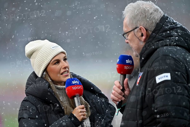 SKY reporter presenter Mara Mones wears cap in interview microphone micro logo with CEO managing director Holger Sanwald 1. FC Heidenheim 1846 FCH portrait snow, blowing snow, winter, Voith-Arena, Heidenheim, Baden-Württemberg, Germany