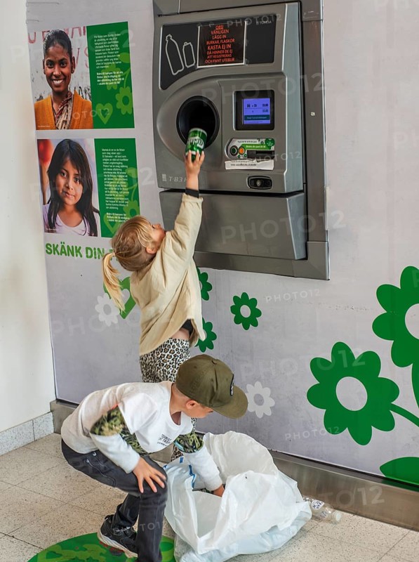 Two children, 5 and 7 years old, earn pocket money by recycling cans in a recycling machine in Ystad, Skåne County, Sweden, Scandinavia