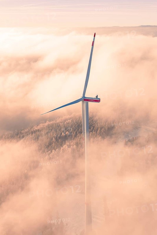Tall wind turbine in fog illuminated by early morning lights, Bad Wildbad, Calw district, Black Forest, Germany