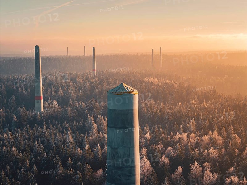 In the distance, smoke-free wind turbine towers stand over thick fog, the winter forest and an orange glow create a peaceful atmosphere, Windkraft Bau, Besenfeld, Seewald, Freudenstadt district, Germany