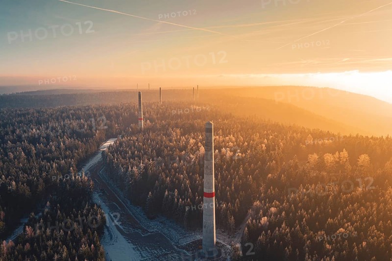 Sun rays over a foggy forest and wind turbine towers rising from the tree cover, Windkraft Bau, Besenfeld, Seewald, Freudenstadt district, Germany