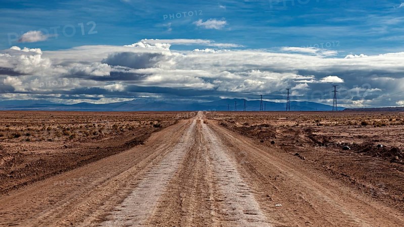 Lonely road stretching into the distance, under a cloudy sky, The landscape of the Altiplano near Uyuni in Bolivia