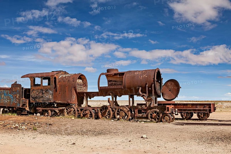 A heavily weathered locomotive with missing parts against a blue sky, old rusty locomotives at the train cemetery near Uyuni in the Altiplano in Bolivia