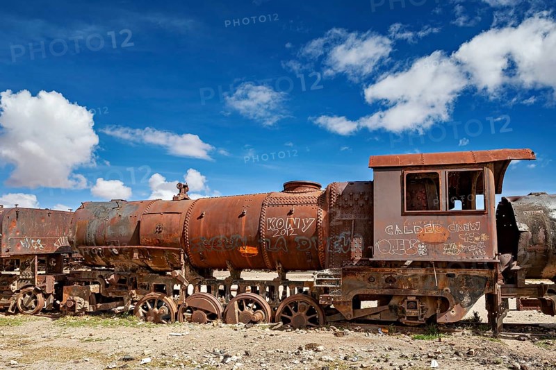 Abandoned and rusty locomotive with graffiti under a dramatically cloudy sky, old rusty locomotives at the train cemetery near Uyuni in the Altiplano in Bolivia