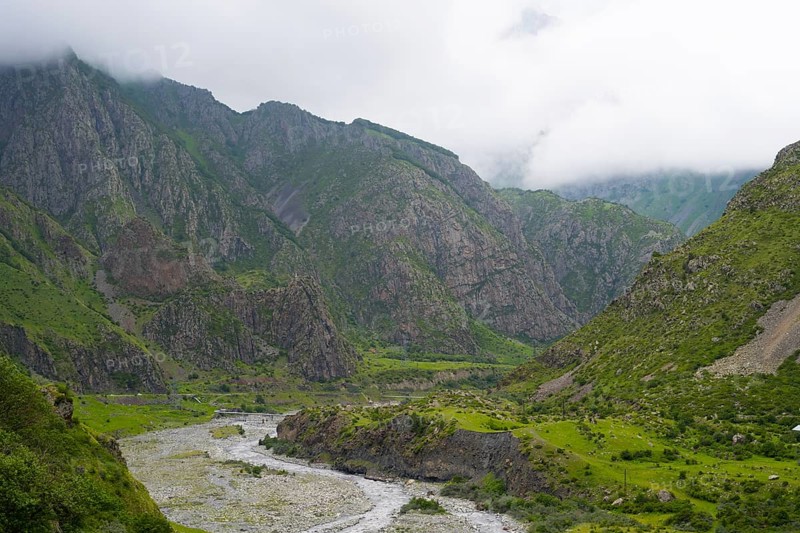 Mighty mountains with cloud cover, a river cuts through the green valley with rocks and vegetation, Tergi River, Terek, Darial Gorge, Dariel Gorge, Kazbegi, Stepansminda, Georgian Military Highway, Mtskheta-Mtianeti Province, High Caucasus, Georgia