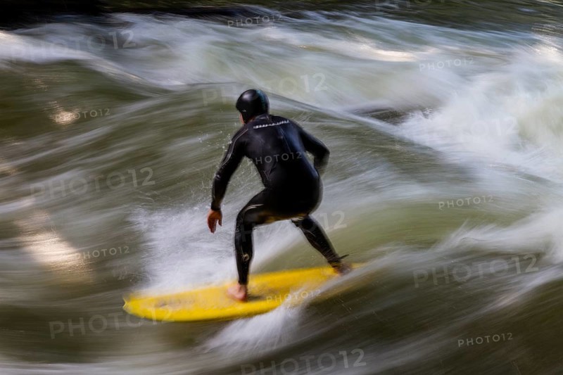 Surfers standing on Eisbach wave in the English Garden Munich, Upper Bavaria, Germany