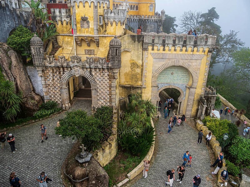Tourists visiting the palace Palácio Nacional da Pena, foggy day, Sintra, Portugal