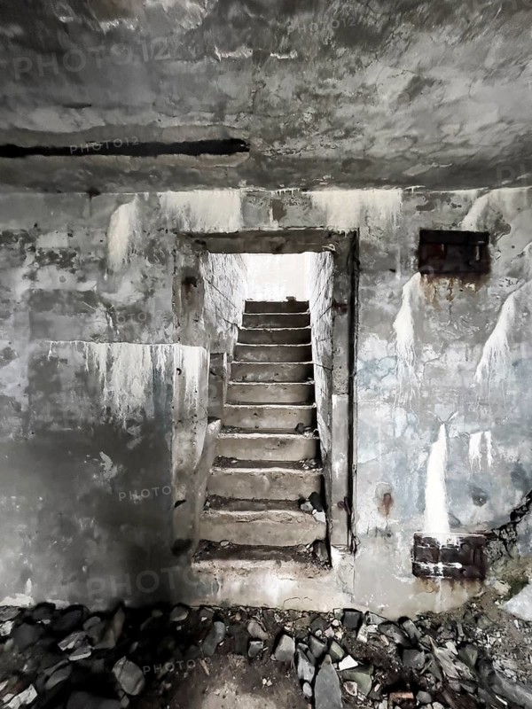 Old Wehrmacht anti-aircraft bunker from the Second World War with worn stairs in a dilapidated, dark environment, Båtsfjord, Finnmark, Norway