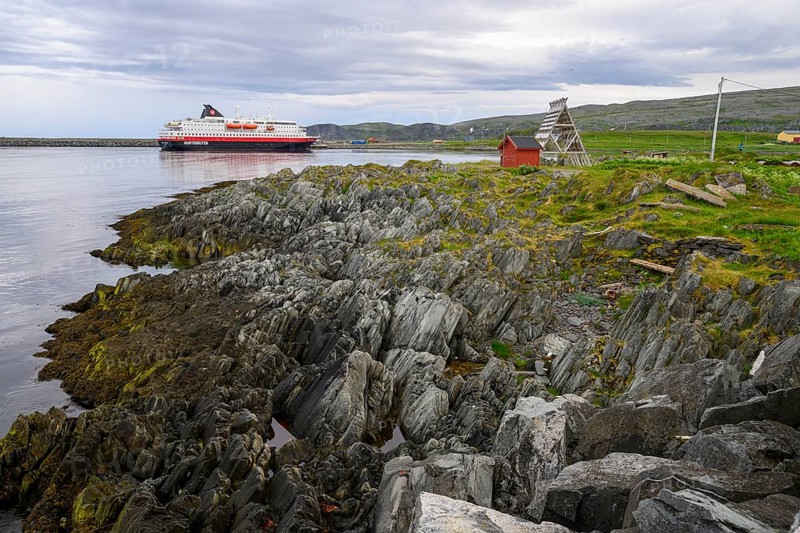 The Hurtigrouten Hurtigruten ship Kong Harald arrives at Berlevag harbour, on the horizon with a cloudy sky, Berlevåg, Finnmark, Norway