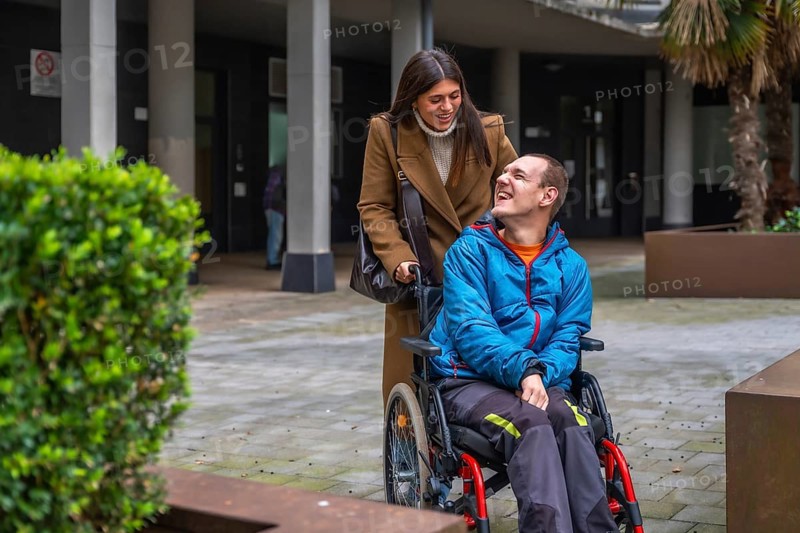 Woman and man with disability smiling outdoors, focusing on happy interaction, personal growth, empowerment, and social inclusion within a supportive and caring community