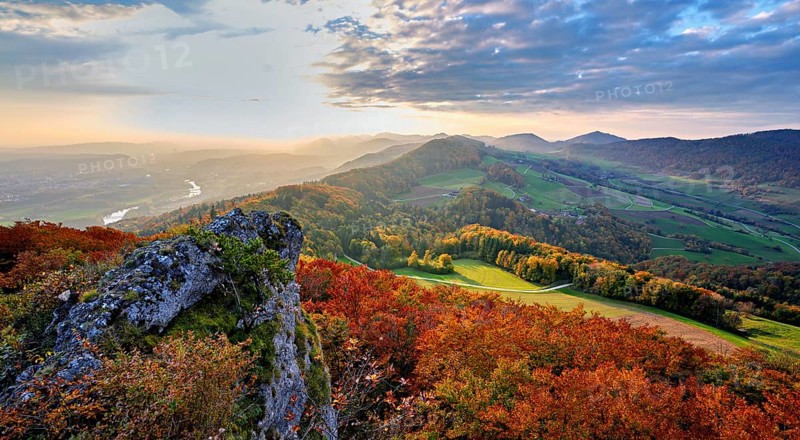 View from the Gisliflue of an autumn-colored forest, behind the Jurassic foothills with water fluh and stripes in the light of the setting sun, Talheim, Canton, Aargau, Switzerland