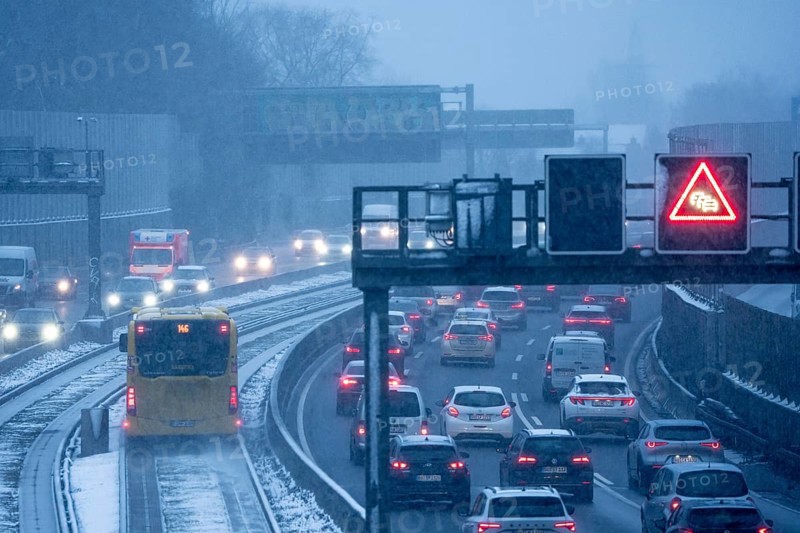Winter weather, motorway traffic, A40 motorway, Ruhrschnellweg, in Essen, at the Essen-East motorway junction, snowfall, traffic jams, heavy flowing traffic, bus lane between roads, public transport, North Rhine-Westphalia, Germany