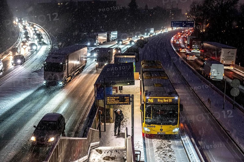 Winter weather, motorway traffic, A40 motorway, Ruhrschnellweg, in Essen, at the Essen-Ost motorway junction, snowfall, traffic jams, heavy flowing traffic, stop, bus lane between lanes, public transport, North Rhine-Westphalia, Germany