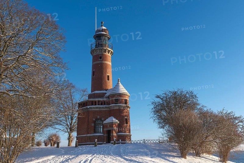 Holtenau lighthouse at the entrance of the Kiel Canal in winter, west bank of the Kiel Fjord, shipping, brick building from 1895, round tower, orientation, sea sign, beacon, ground floor with wedding room, trees, snow, blue sky, Baltic Sea, Kiel, Germany