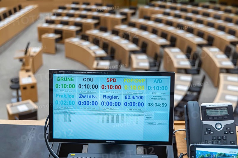 Plenary hall deserted with the seats of deputies and the government bank. Behind it is the country's coat of arms. The speaking time of members of the parties is recorded and documented down to the second. The state parliament of Baden-Württemberg is the state parliament based in Stuttgart, Baden-Württemberg, Germany