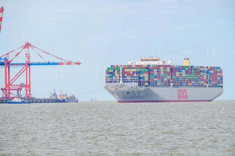 The container ship OOCL Germany with 59 m width and 400 m length of one of the largest container ships in the world maneuvers between cranes in Jade Weser Port, Wilhelmshafen, Jade Bay, Lower Saxony, Germany