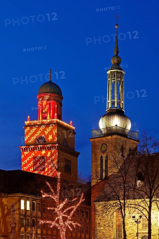 The Christmassy illuminated town hall tower and the illuminated church tower of St. John's Church in Witten, Ruhr area, North Rhine-Westphalia, Germany