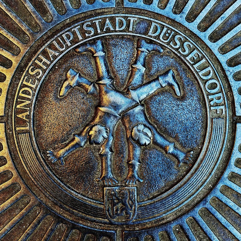 Manhole cover with classic depiction of the racket, landmark of the state capital Düsseldorf, North Rhine-Westphalia, Germany