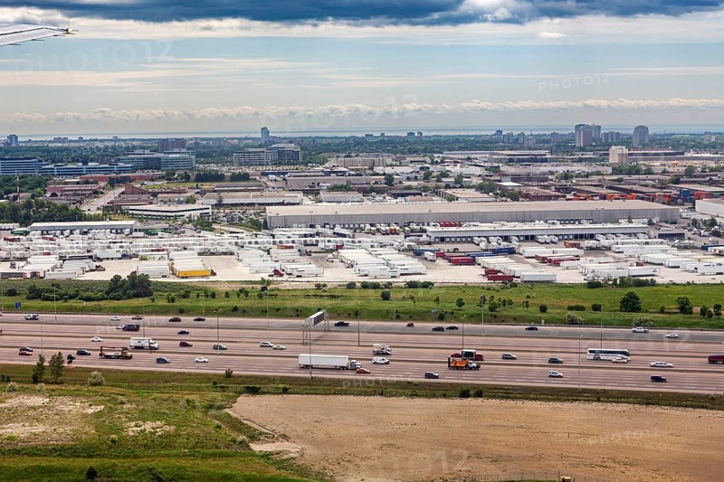 An industrial cityscape with a busy highway and overlying clouds, view from an airplane of the suburbs of Toronto in Canada