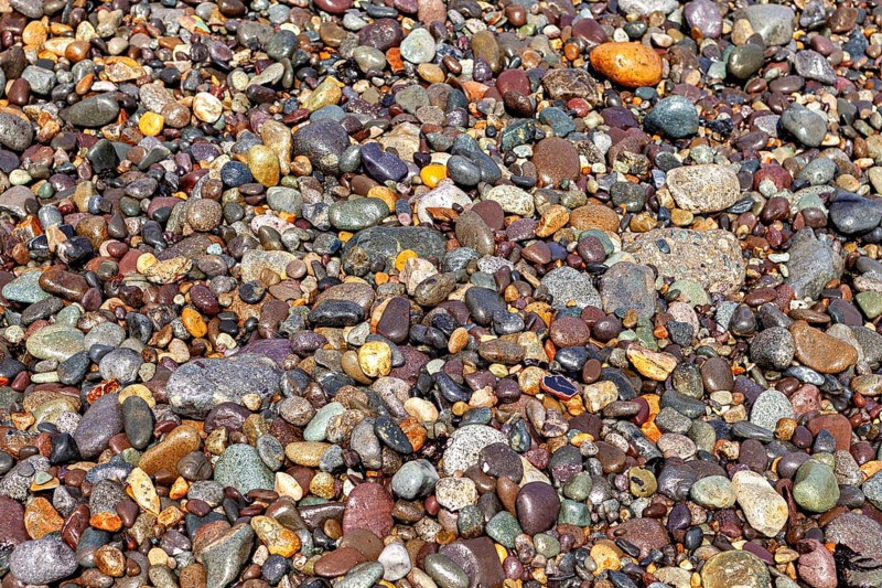 A variety of colorful pebbles of various shapes and colors form a natural texture. The colorful gravel on the beach on the coast near Lima in Peru