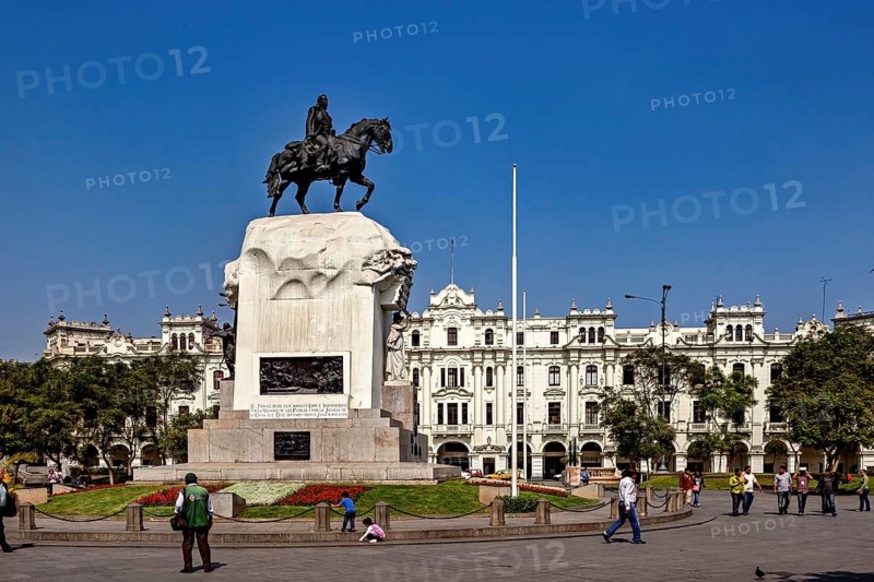 Equestrian statue in front of a flower-decorated base in a square with white buildings, Downtown Lima in Peru