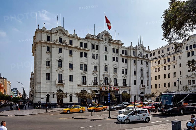 Large white building with national flag surrounded by vehicles and trees, Downtown Lima in Peru
