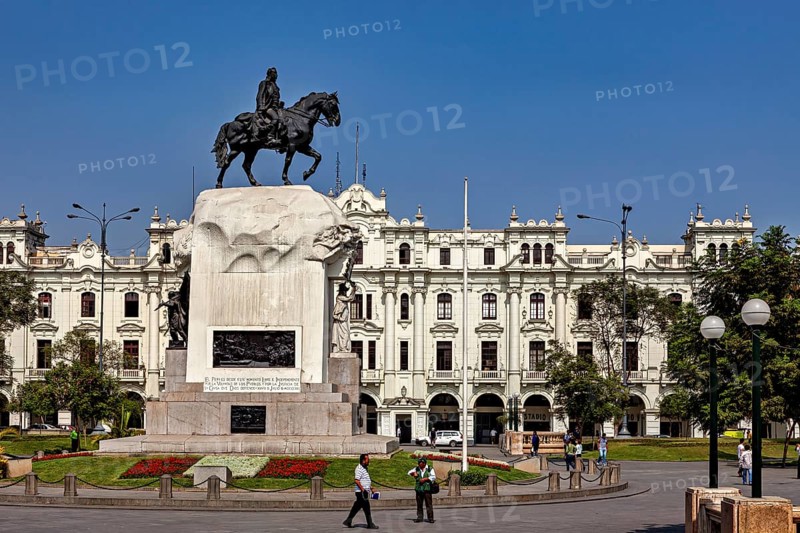 Equestrian statue on a large pedestal in front of an imposing historic building under a blue sky, Downtown Lima in Peru