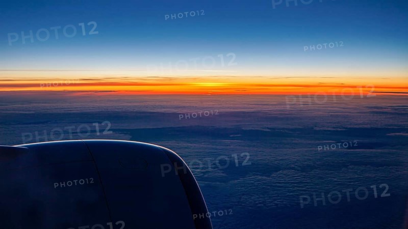 Sunset with dark sky and aircraft engine, On a plane above the clouds