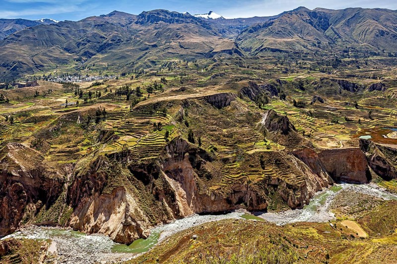 Mountain landscape with terraced fields and a river surrounded by green nature under blue skies, The landscape of the Colca Canyon in the Andes of Peru