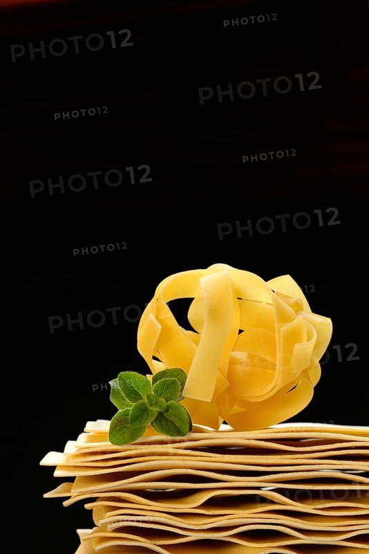 Uncooked lasagna leaves and fettuccine, noodle nest