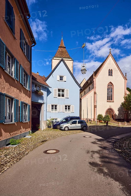 St. Martin parish church, church tower, houses, historic residential buildings, apartment buildings, street, curve, cars, trees, blue sky, cumulus clouds, Kirchstraße, Staufen im Breisgau, Black Forest, Breisgau-Hochschwarzwald district, Baden-Württemberg, Germany