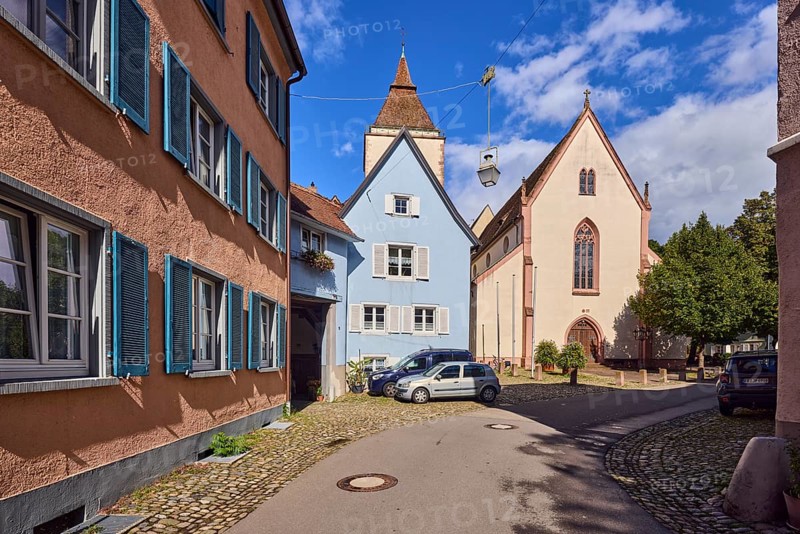 St. Martin parish church, church tower, houses, historic residential buildings, apartment buildings, street, curve, cars, trees, blue sky, cumulus clouds, Kirchstraße, Staufen im Breisgau, Black Forest, Breisgau-Hochschwarzwald district, Baden-Württemberg, Germany
