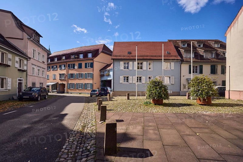 Houses, residential buildings, apartment buildings, façade with windows and shutters, dormers, church, flower pot, street, barrier bollard, curve, blue sky, cumulus clouds, Kirchstraße, Staufen im Breisgau, Black Forest, Breisgau-Hochschwarzwald district, Baden-Württemberg, Germany