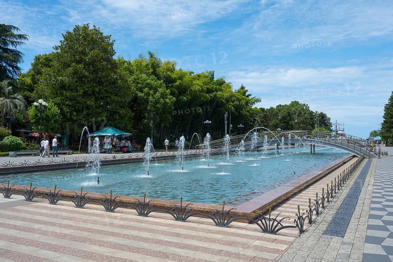 Fountain with walkway and trees in urban landscape under blue sky, Batumi Boulevard, Batumi, Black Sea, Ajara region, Adjara, Autonomous Republic, Georgia