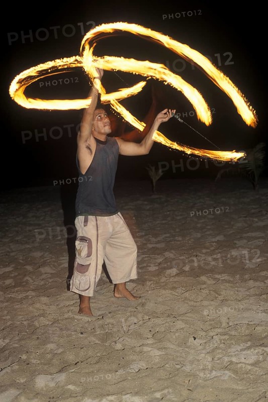 A man waves burning torches on the beach of Coral Beach Resort on the island of Ko Lanta, Thailand, December 2002, vintage, retro, old, historic