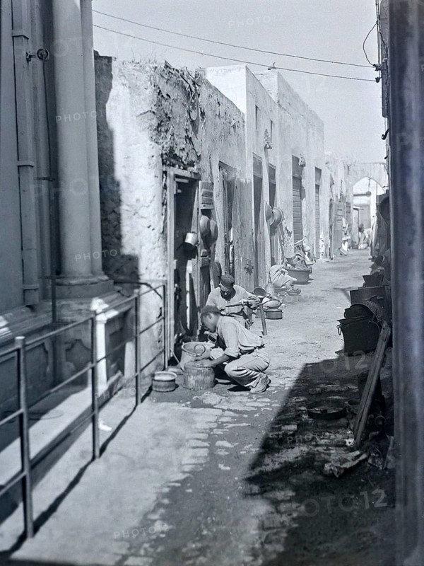 Workers with metal pots in narrow alleyway street in old town medina, Tripoli, Libya, North Africa 1956